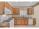 Bright kitchen showcasing granite countertops, white appliances, wood cabinets and shutters at 7916 Lyrebird Dr, North Las Vegas, NV 89084