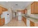 Well-lit kitchen featuring granite countertops, wooden cabinets, white appliances, and tile flooring at 7916 Lyrebird Dr, North Las Vegas, NV 89084