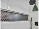 A modern designed shower features white tile and black honeycomb accent stripe at 882 Tam O Shanter, Las Vegas, NV 89109