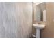 Modern powder room boasts white textured tile, a pedestal sink, and a decorative mirror at 9850 Poplar Point Ave, Las Vegas, NV 89178