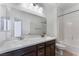 Bathroom showcasing a double vanity, large mirror, modern lighting, and a tub with shower at 9850 Poplar Point Ave, Las Vegas, NV 89178