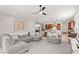 Open-concept living room featuring a gray sectional sofa, ceiling fan, and view of the modern kitchen at 10160 Tree Blossom Ave, Las Vegas, NV 89166