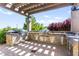 Outdoor kitchen featuring stainless steel appliances, stone backsplash, and paver patio at 10160 Tree Blossom Ave, Las Vegas, NV 89166