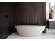 Freestanding soaking tub with dark wood accent wall, in modern bathroom at 1429 Iron Hills Ln, Las Vegas, NV 89134