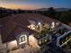 Luxury home boasts a tile roof, manicured landscape, and outdoor seating with a fire pit at dusk at 1429 Iron Hills Ln, Las Vegas, NV 89134