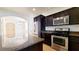 Modern kitchen with dark cabinets, stainless steel appliances, and a granite-topped island overlooking the living area at 145 Forest Crossing Ct, Las Vegas, NV 89148