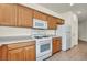 Well-lit kitchen features wooden cabinets, white appliances, and tile flooring at 1604 Lazy Hill Ranch Way, North Las Vegas, NV 89081