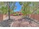 A backyard with desert landscaping is framed by mature trees and a brick perimeter fence at 229 N Buteo Woods Ln, Las Vegas, NV 89144