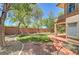 Spacious backyard featuring a patio area, a well-maintained lawn, and mature trees at 229 N Buteo Woods Ln, Las Vegas, NV 89144