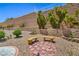 Serene backyard with retaining wall, desert landscaping, and charming benches for relaxation at 2413 Rockford St, Las Vegas, NV 89134