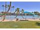Community beach with clear water, palm trees, umbrellas, and lounge chairs for residents to enjoy at 2528 Huber Heights Dr, Las Vegas, NV 89128
