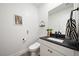 Modern powder room with a white vanity cabinet, black countertop, and stylish decorative accents at 2722 Marchetti Pl, Henderson, NV 89044