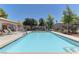 Community pool surrounded by lounge chairs, lush greenery, and a fence at 278 Star Cluster Cir, Las Vegas, NV 89145