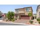 Tan two-story home with a brick driveway and landscaping at 4498 Lantern Point Ave, North Las Vegas, NV 89084
