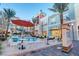 Community pool surrounded by umbrellas, tables, and chairs and shops in the background at 511 Beaconwood St, Henderson, NV 89052