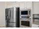 Stainless steel refrigerator, microwave, and oven appliances in a kitchen with stone countertops and white cabinets at 511 Beaconwood St, Henderson, NV 89052