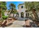 Elegant home entrance with a decorative door and desert landscaping featuring palm trees and rock accents at 5224 Painted Lakes Way, Las Vegas, NV 89149