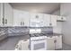 A modern kitchen featuring white cabinets, tile backsplash, and stainless steel appliances at 5425 Thomaston Ct, Las Vegas, NV 89122