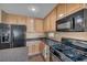 Close-up of kitchen with black appliances, light wood cabinets and dark countertops at 582 Brompton St, Las Vegas, NV 89178
