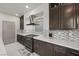 Modern kitchen with stainless appliances, cooktop, dark cabinets, quartz counters and stylish backsplash at 6618 Tangled Vines Ave, Las Vegas, NV 89139