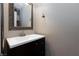 Small powder room with dark vanity, modern white sink, and ornate mirror at 700 Red Bark Ln, Henderson, NV 89011