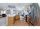 Open kitchen with stainless steel appliances, wood cabinets, wood-look floors, and adjacent living area at 700 Red Bark Ln, Henderson, NV 89011