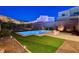 Beautiful backyard with a modern pool, spa, fire pit, and lush green lawn at 734 Glowing Horizon St, Henderson, NV 89052