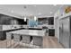 Modern kitchen featuring dark cabinets, a large island with seating, stainless steel appliances, and stylish backsplash at 8072 Haywood Estate, Las Vegas, NV 89113