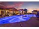 Stunning backyard pool with illuminated water, covered patios, lush landscaping at sunset at 9385 Mohawk St, Las Vegas, NV 89139