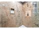 Close up of a shower with granite walls, a shower head, and shower supplies in the niche at 9385 Mohawk St, Las Vegas, NV 89139
