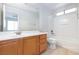 Well-lit bathroom features a tub and shower combination, a wooden vanity, and a tiled floor at 9814 Gifthouse St, Las Vegas, NV 89178