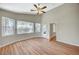 Bright bedroom featuring wood-look floors, neutral paint, ceiling fan, and backyard views at 10198 Timber Willow Ave, Las Vegas, NV 89135