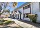 Two-story townhome with white walls, red trim, and desert landscaping, sidewalk and some trees at 225 Pecos Way, Las Vegas, NV 89121