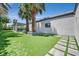 Well-manicured backyard featuring a pristine lawn, a covered patio, and lush tropical landscaping with palm trees at 324 Park Way, Las Vegas, NV 89106