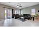 Spacious living room with tile flooring, comfortable seating, ceiling fan, and sliding door to outdoor patio at 4523 Herbert River Ave, Las Vegas, NV 89141