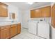 The laundry room features modern washer, dryer, tile flooring, and wood cabinets for storage at 5981 Doubletree Rd, Pahrump, NV 89061