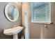 Bathroom with pedestal sink, round mirror, and window with blinds at 6125 Broken Slate Way, Las Vegas, NV 89139