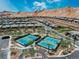 Aerial view featuring tennis courts, lush landscaping, mountain views, and attractive single-Gathering homes at 64 Lake Oasis St, Henderson, NV 89011