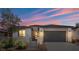 Charming home with a gray exterior, black garage door and desert landscaping at 64 Lake Oasis St, Henderson, NV 89011