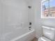Clean bathroom featuring a white tiled shower-tub combo and toilet at 6456 First View Ave, Las Vegas, NV 89142