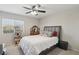Cozy bedroom featuring a ceiling fan, a comfortable bed, and a vanity with natural light from the window at 7640 Woven Memories St, Las Vegas, NV 89149