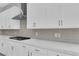Modern kitchen featuring stainless steel hood and gray backsplash with all-white cabinetry at 851 Klamath Springs St, Henderson, NV 89011