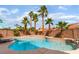 Inviting pool surrounded by lush palm trees, rock waterfall feature, and desert landscaping at 8605 Trianon Ln, Las Vegas, NV 89145