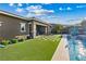 Beautiful backyard showcasing a well-maintained lawn, swimming pool, covered patio, and mountain views in the distance at 9972 Terrastone Dr, Las Vegas, NV 89148