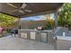 Outdoor kitchen featuring a grill, mini fridge, and countertop space, all set under a covered patio with ceiling fan at 9972 Terrastone Dr, Las Vegas, NV 89148