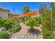 Beautifully landscaped backyard with brick pathway, lush greenery, and shade umbrella at 1145 Glacier Park Ct, Henderson, NV 89052