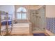 Bathroom featuring a soaking tub with arched window and tiled walk-in shower with frameless glass door at 1145 Glacier Park Ct, Henderson, NV 89052