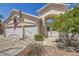 Inviting home exterior with three-car garage and an arched entryway enhanced by mature landscaping and an American flag at 1145 Glacier Park Ct, Henderson, NV 89052