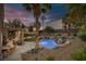 Lush backyard with a rock waterfall feature pool, palm trees, ambient lighting, and comfortable patio furniture at 1246 Diamond Valley St, Henderson, NV 89052
