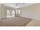 Cozy living room featuring neutral carpet, a ceiling fan, and sliding glass doors to the backyard at 2508 Chasma Dr, Henderson, NV 89044